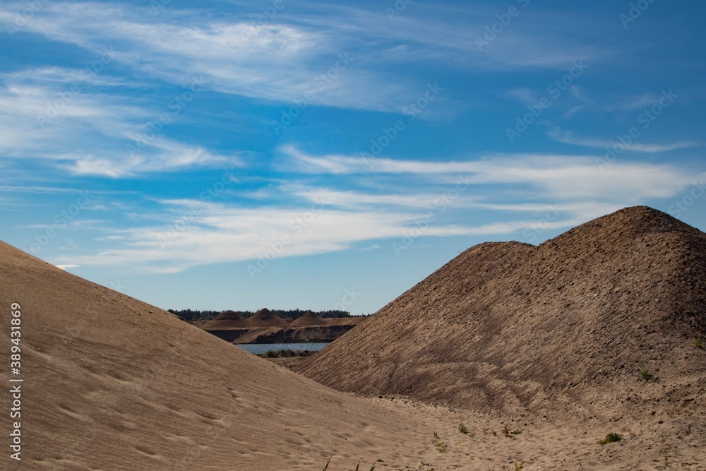 Sand dunes in a desert with a lake in the background