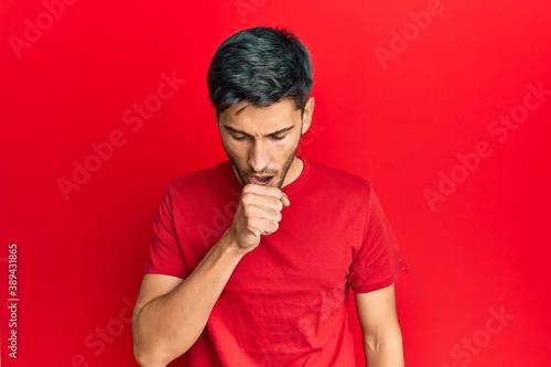 Young handsome man wearing casual tshirt over red background feeling unwell and coughing as symptom for cold or bronchitis. health care concept.