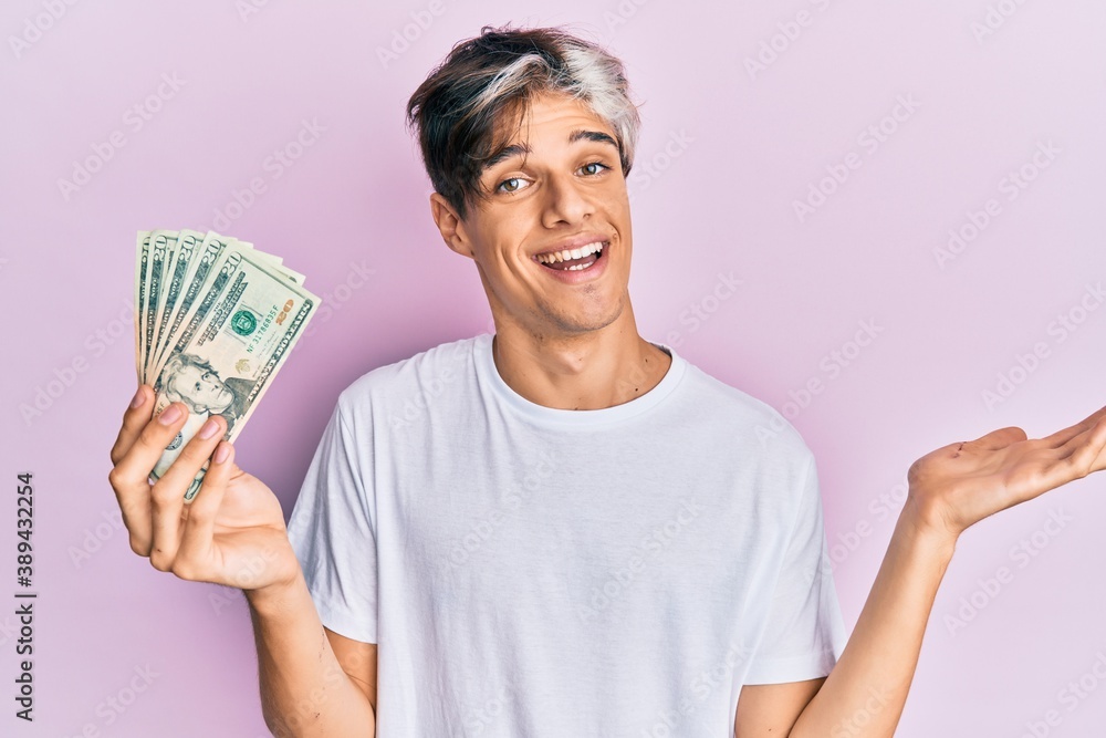 Young hispanic man holding 20 dollars banknote celebrating achievement with happy smile and winner expression with raised hand Young hispanic man holding 20 dollars banknote celebrating achievement with happy smile and winner expression with raised hand