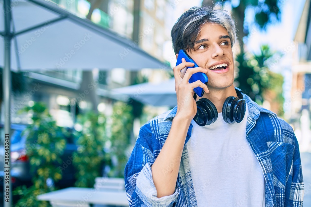 Young hispanic man smiling happy talking on the smartphone and using headphones at the city. Young hispanic man smiling happy talking on the smartphone and using headphones at the city.