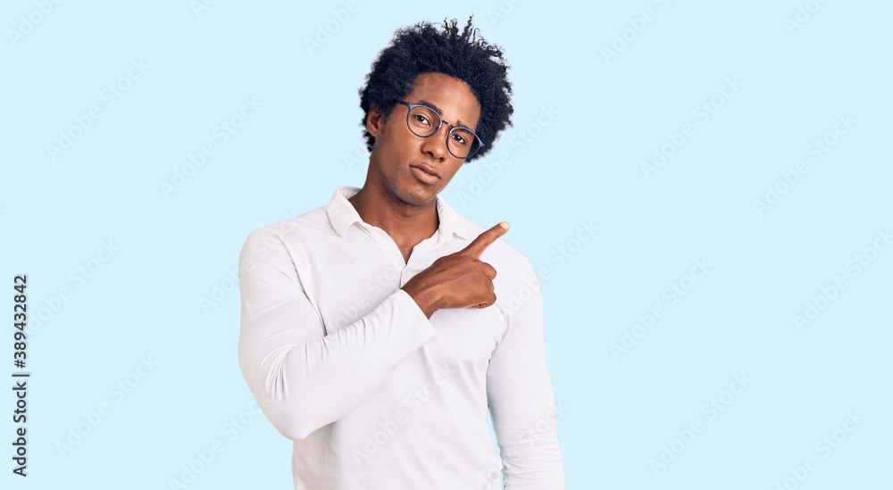 Handsome african american man with afro hair wearing casual clothes and glasses pointing with hand finger to the side showing advertisement, serious and calm face Handsome african american man with afro hair wearing casual clothes and glasses pointing with hand finger to the side showing advertisement, serious and calm face