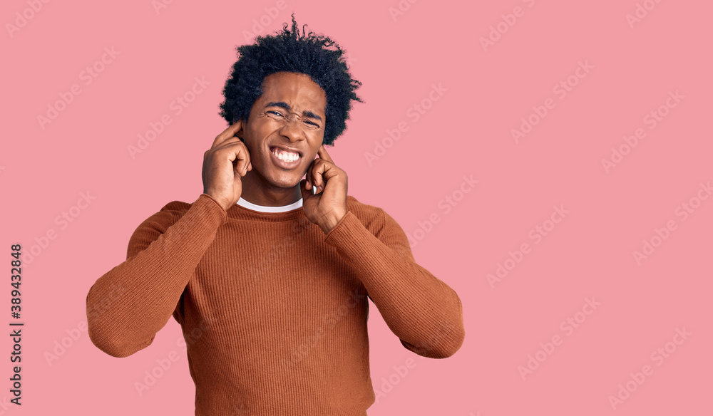 Fototapeta premium Handsome african american man with afro hair wearing casual clothes covering ears with fingers with annoyed expression for the noise of loud music. deaf concept.