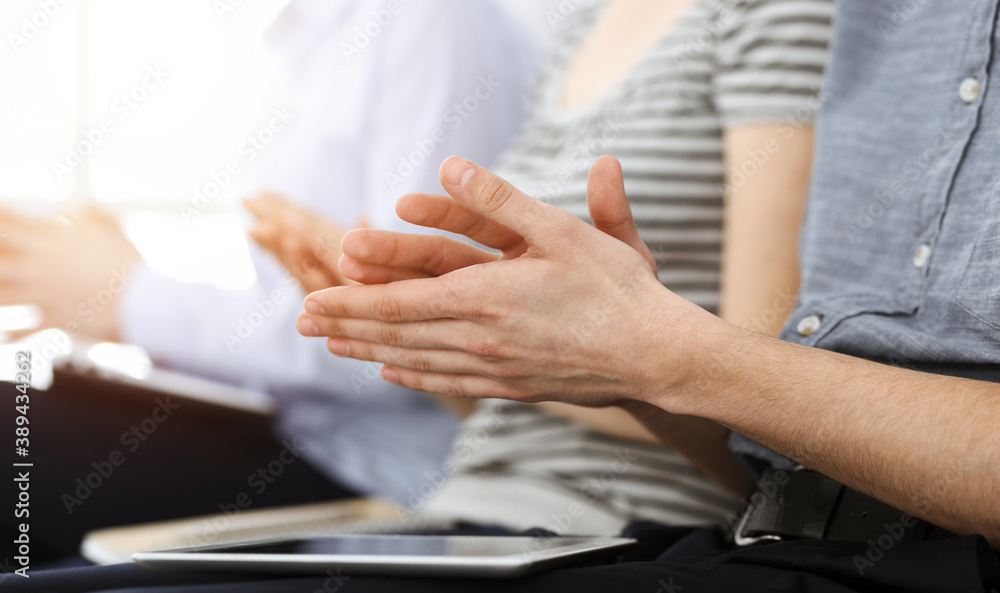 Obraz premium Business people clapping at meeting or conference, close-up of hands. Group of unknown businessmen and women in sunny office
