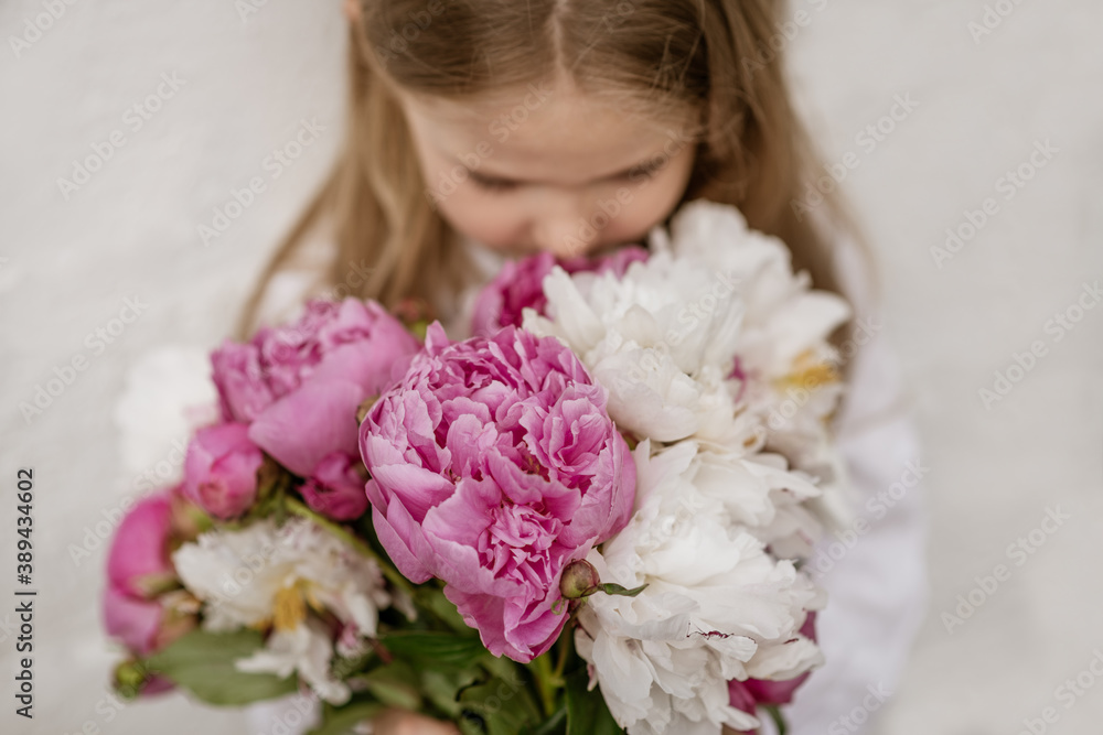 Portrait of a little girl smelling the peonies