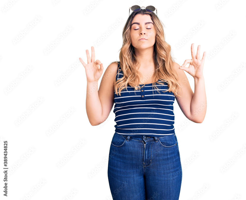 Young caucasian woman wearing casual clothes and sunglasses relax and smiling with eyes closed doing meditation gesture with fingers. yoga concept. Young caucasian woman wearing casual clothes and sunglasses relax and smiling with eyes closed doing meditation gesture with fingers. yoga concept.