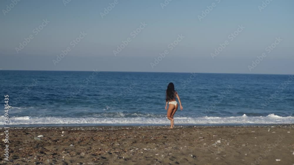 Happy Female in Swimsuit Running on Beach by Mediterranean Sea, Wide Full Frame Shot Happy Female in Swimsuit Running on Beach by Mediterranean Sea, Wide Full Frame Shot