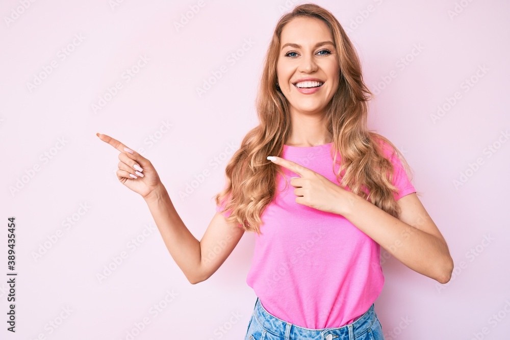 Young caucasian woman with blond hair pointing with fingers to the side smiling with a happy and cool smile on face. showing teeth. Young caucasian woman with blond hair pointing with fingers to the side smiling with a happy and cool smile on face. showing teeth.