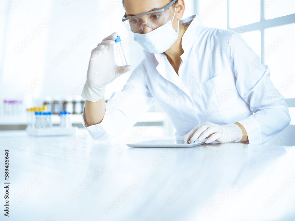 Female laboratory assistant analyzing a blood sample at hospital. Medicine, health care and researching concept Female laboratory assistant analyzing a blood sample at hospital. Medicine, health care and researching concept