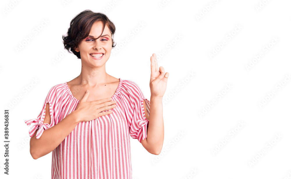Beautiful young woman with short hair wearing casual summer clothes smiling swearing with hand on chest and fingers up, making a loyalty promise oath Beautiful young woman with short hair wearing casual summer clothes smiling swearing with hand on chest and fingers up, making a loyalty promise oath