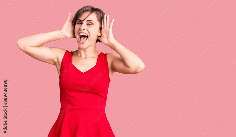 Beautiful young woman with short hair wearing casual style with sleeveless shirt smiling cheerful playing peek a boo with hands showing face. surprised and exited Beautiful young woman with short hair wearing casual style with sleeveless shirt smiling cheerful playing peek a boo with hands showing face. surprised and exited