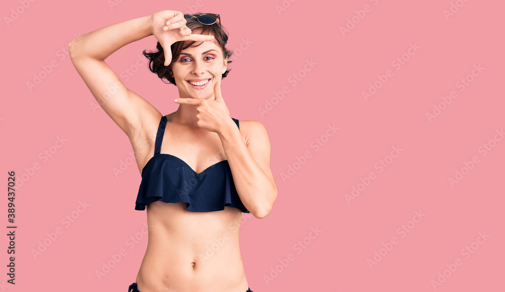 Naklejka premium Beautiful young woman with short hair wearing bikini smiling making frame with hands and fingers with happy face. creativity and photography concept.