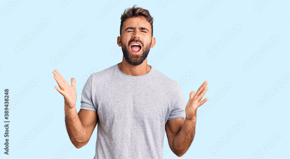 Young hispanic man wearing casual clothes celebrating mad and crazy for success with arms raised and closed eyes screaming excited. winner concept Young hispanic man wearing casual clothes celebrating mad and crazy for success with arms raised and closed eyes screaming excited. winner concept