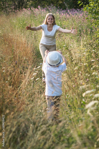 Happy family mother and son enjoying walk together at meadow in summer