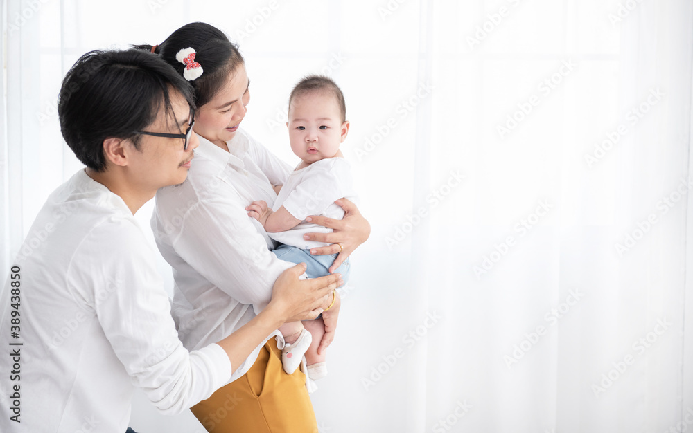 Smiling asian father and mother holding their baby son at home. Proud asia mother and father with daughter infant on white background. family people happy concept Smiling asian father and mother holding their baby son at home. Proud asia mother and father with daughter infant on white background. family people happy concept