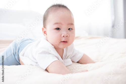 Portrait of a crawling baby on the bed. Happy asian infant in bedroom.