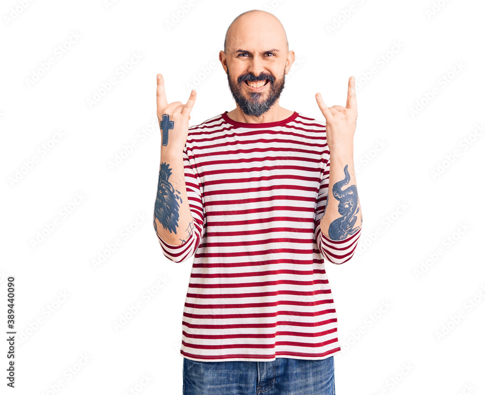 Young handsome man wearing casual clothes shouting with crazy expression doing rock symbol with hands up. music star. heavy concept. Young handsome man wearing casual clothes shouting with crazy expression doing rock symbol with hands up. music star. heavy concept.