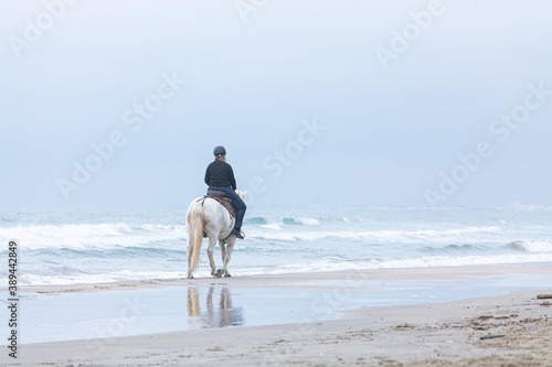 woman on a horse on the beach on a cloudy day