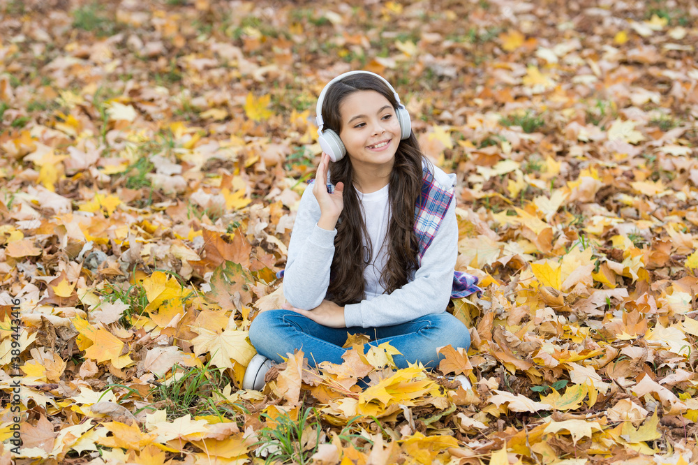 Relaxing yourself music to help you rest. Happy kid listen to music sitting on autumn leaves. Fun and entertainment. Leisure activities. Modern life and technology. Fresh air relax. Hear it, enjoy it Relaxing yourself music to help you rest. Happy kid listen to music sitting on autumn leaves. Fun and entertainment. Leisure activities. Modern life and technology. Fresh air relax. Hear it, enjoy it