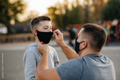 A father puts a mask on his son on the Playground after training during sunset