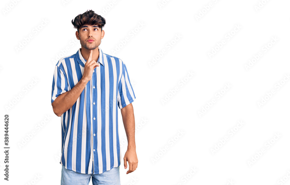 Young hispanic man wearing casual clothes thinking concentrated about doubt with finger on chin and looking up wondering Young hispanic man wearing casual clothes thinking concentrated about doubt with finger on chin and looking up wondering
