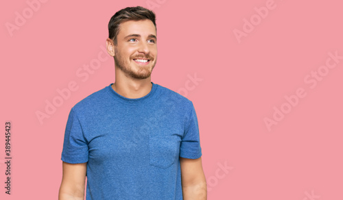 Obraz na plátně Handsome caucasian man wearing casual clothes looking away to side with smile on face, natural expression