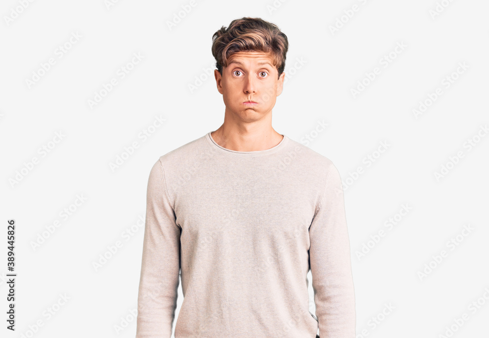Young handsome man wearing casual clothes puffing cheeks with funny face. mouth inflated with air, crazy expression. Young handsome man wearing casual clothes puffing cheeks with funny face. mouth inflated with air, crazy expression.