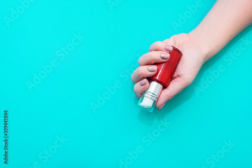 Beautiful women's hands with a delicate manicure hold a bottle of cream. View from above Is a place for text.
