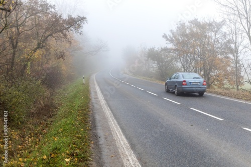 Cars in the fog. Bad autumn weather and dangerous automobile traffic on the road. Light vehicles in fog. Slippery road. Dangerous driving.