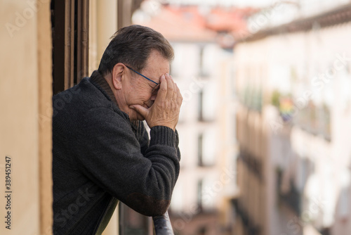 lifestyle portrait of sad and depressed mature man 65 to 70 years old at home balcony feeling lonely and confused facing getting old and retirement alone looking away thoughtful