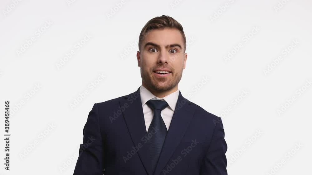 surprised attractive man in navy blue suit opening mouth and making thumbs up gesture, smiling and standing isolated on white background in studio surprised attractive man in navy blue suit opening mouth and making thumbs up gesture, smiling and standing isolated on white background in studio