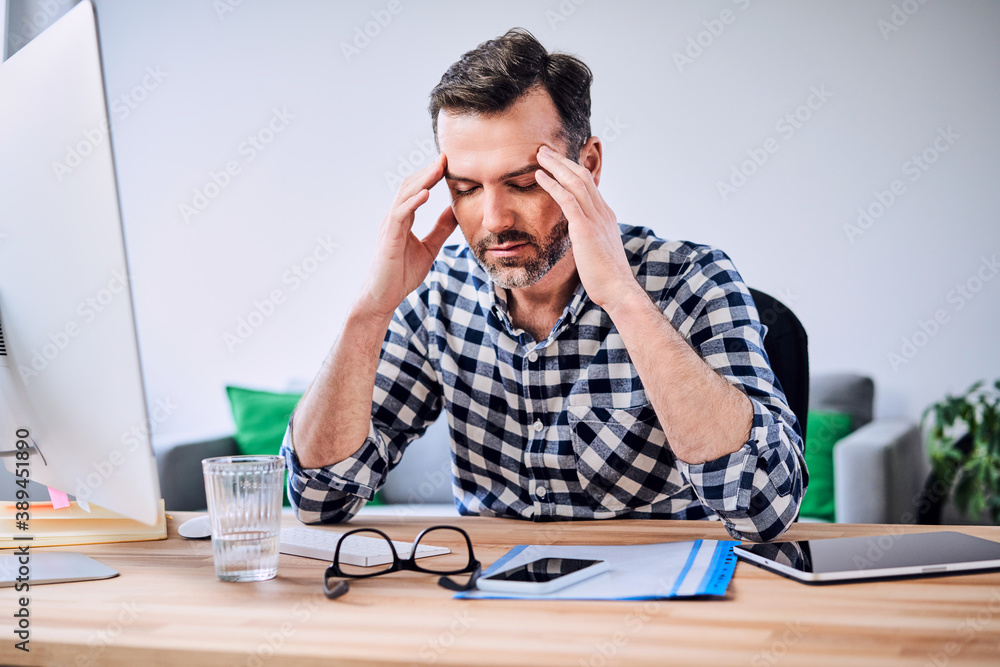 Fototapeta premium Man having headache while working from home