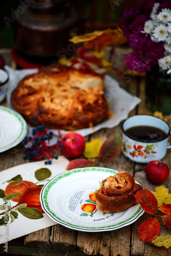 Apple buns with caramel on a wooden table in an autumn garden