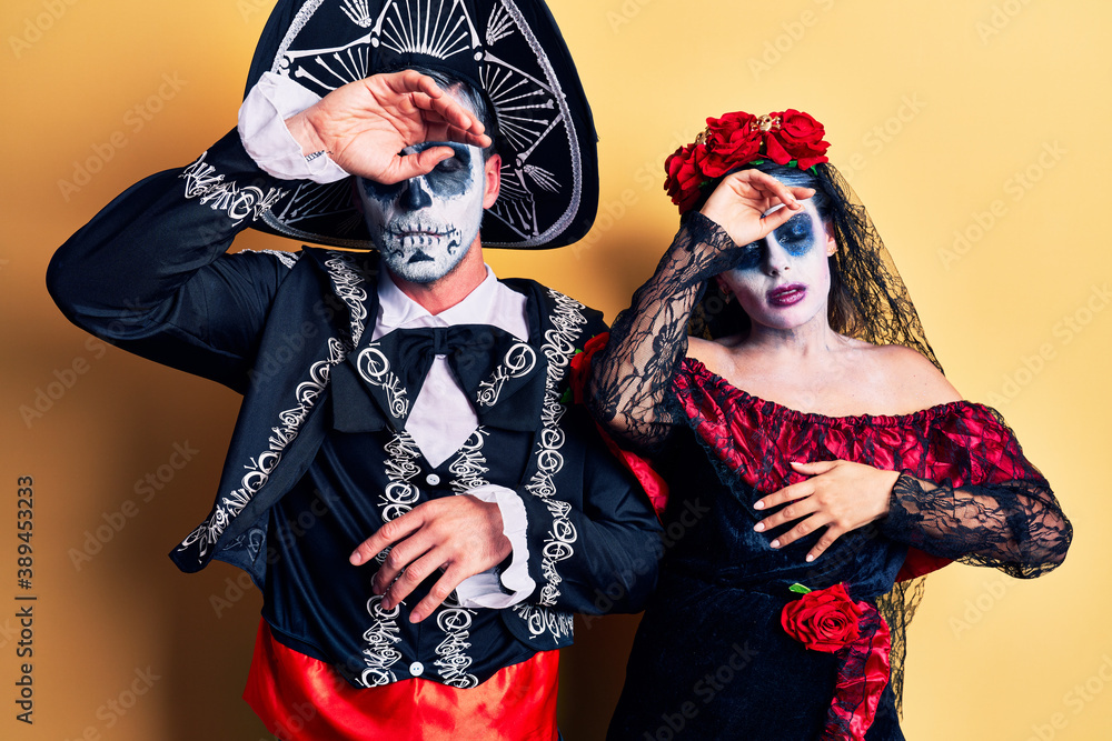 Young couple wearing mexican day of the dead costume over yellow touching forehead for illness and fever, flu and cold, virus sick