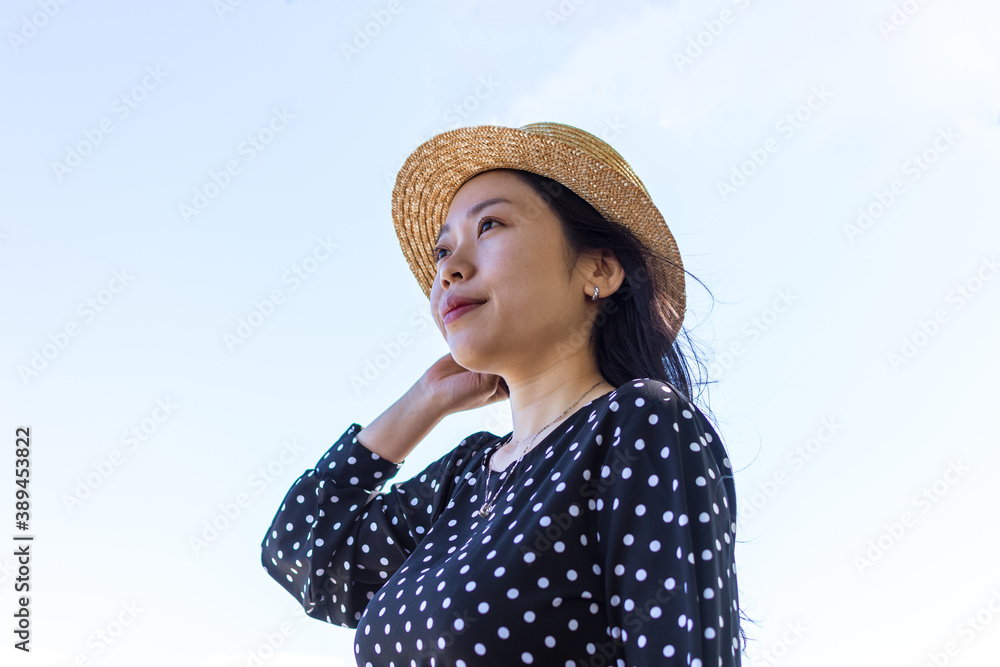 Asian woman gazing out against a plain clear sky. Optimistic, hopeful, youthful concept.