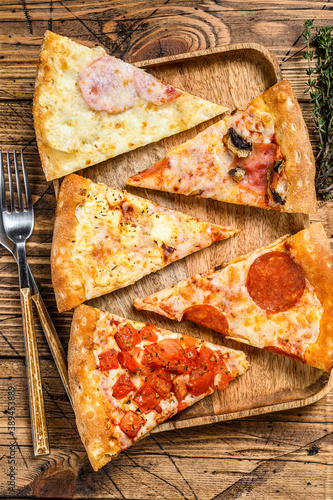 Pieces of different pizza various types. Wooden background. Top view