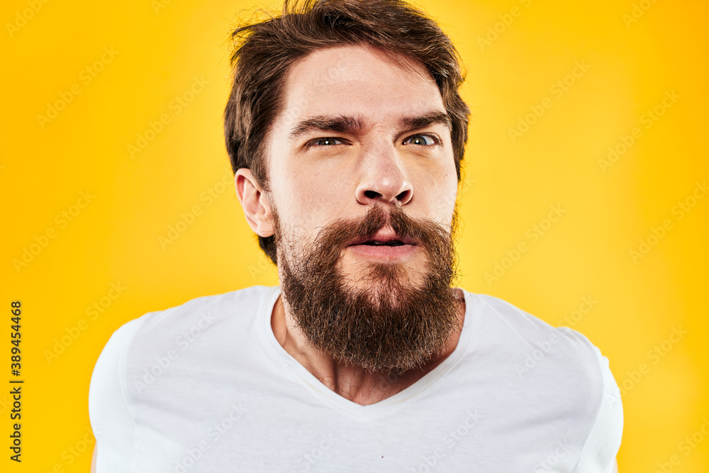 emotional bearded man gesturing with hands aggression discontent close-up yellow background