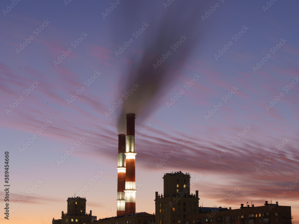 Heat station pipes, smoke. Smoking pipes, gray smoke with violet winter sky as background. Chimneys, concept of industry and ecology, heating season, global warming