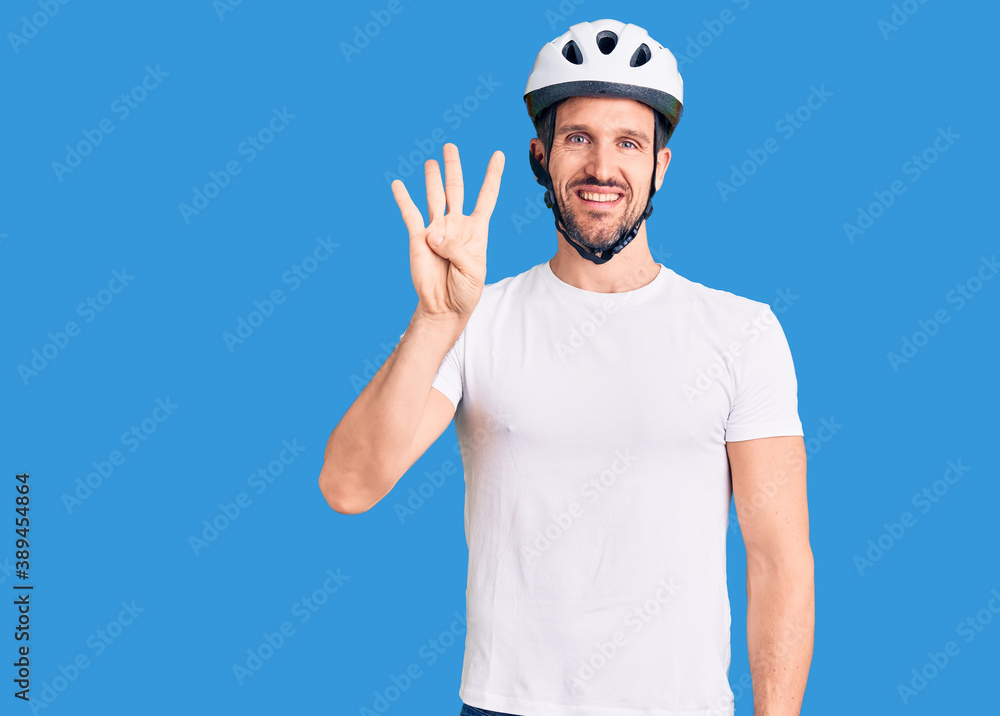 Young handsome man wearing bike helmet showing and pointing up with fingers number four while smiling confident and happy. Young handsome man wearing bike helmet showing and pointing up with fingers number four while smiling confident and happy.