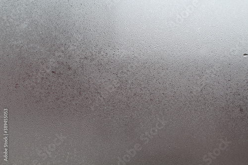 Closeup photo of a foggy window glass in drops of water.