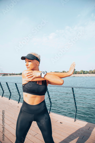 Woman in sportswear doing exercises near the river. Healthy lifestyle concept.