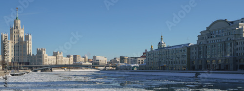 Moscow cityscape in winter sunny day. Stalinist skyscraper, Moskva river had been covered by ice floes. Kotelnicheskaya and Raushskaya embankment. Bolshoy Ustinsky Bridge. © Yury and Tanya