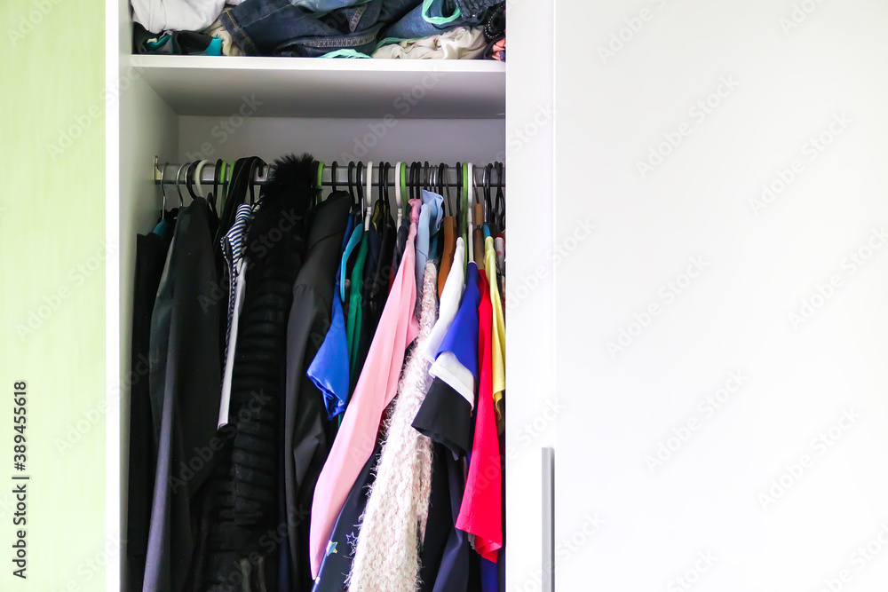 Colorful clothes hanging on hangers at the home wardrobe Colorful clothes hanging on hangers at the home wardrobe