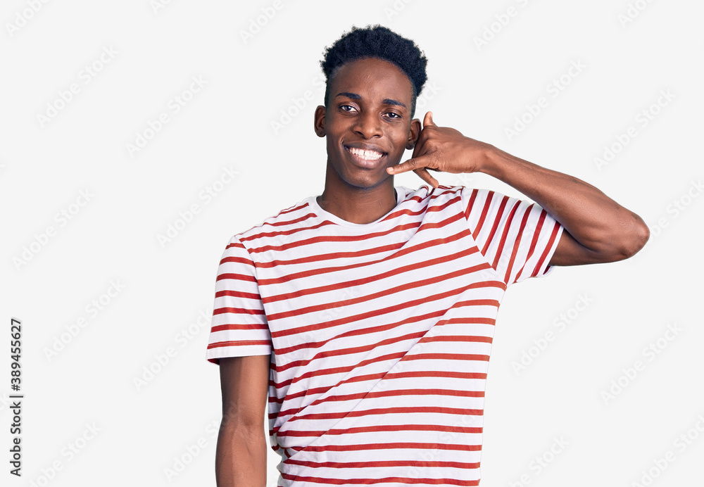 Young african american man wearing casual clothes smiling doing phone gesture with hand and fingers like talking on the telephone. communicating concepts. Young african american man wearing casual clothes smiling doing phone gesture with hand and fingers like talking on the telephone. communicating concepts.