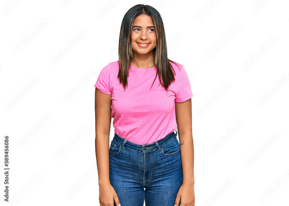 Obraz premium Young latin girl wearing casual clothes looking away to side with smile on face, natural expression. laughing confident.