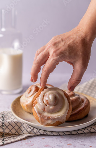 Hungry woman's hand intending to catch a freshly baked cinnamon roll