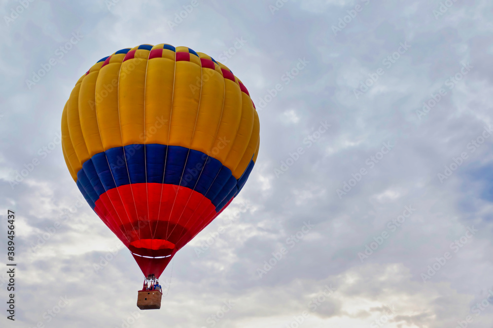 Fototapeta premium Striped yellow blue red balloon against cloudy sky
