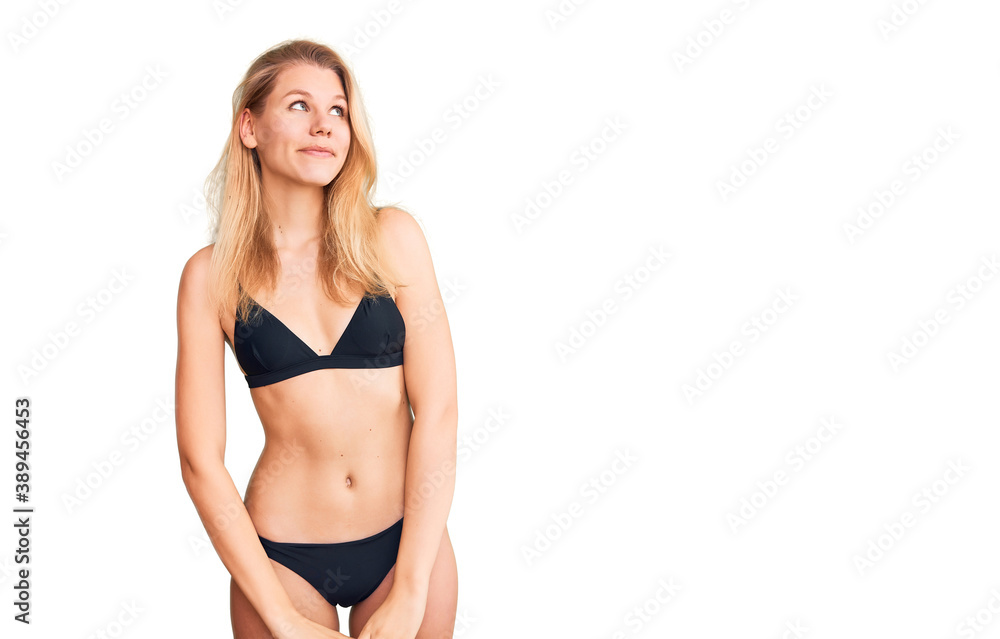 Obraz premium Young beautiful blonde woman wearing bikini smiling looking to the side and staring away thinking.