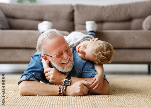 Cheerful kid boy hugging grandfather at home. photo