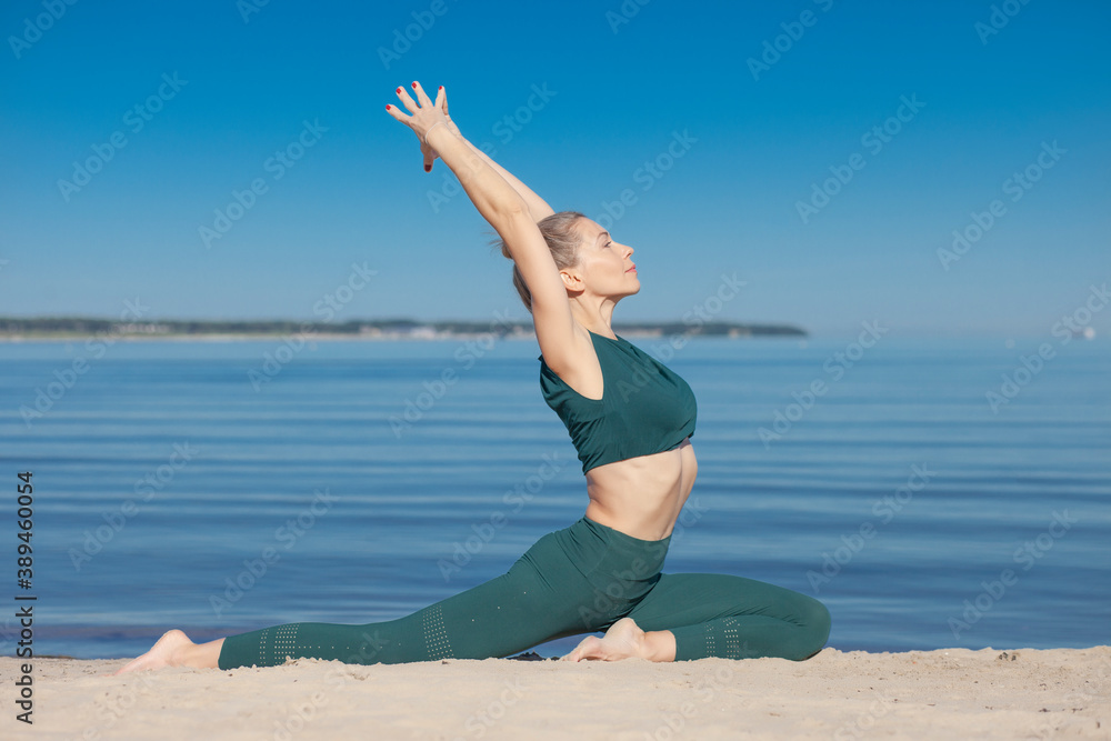 Woman in green sportswear practices yoga by sea Woman in green sportswear practices yoga by sea