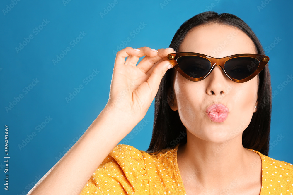 Beautiful woman wearing sunglasses on blue background Beautiful woman wearing sunglasses on blue background